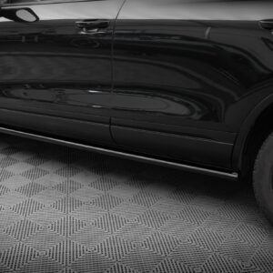 Close-up of a glossy black car door and front wheel on a textured showroom floor.