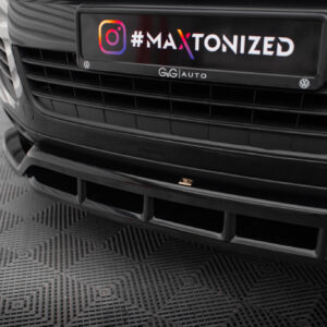 Close-up of a car front showing a black license plate area with the colorful gradient text '#MAXTONIZED' and small VW emblems on either side.