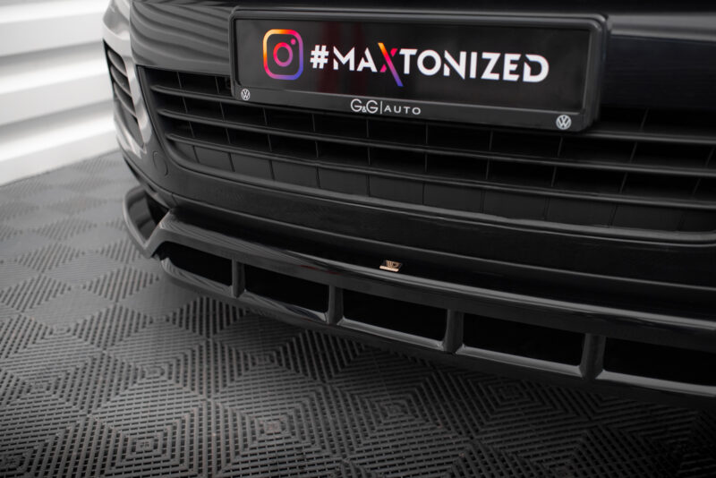 Close-up of a car front showing a black license plate area with the colorful gradient text '#MAXTONIZED' and small VW emblems on either side.