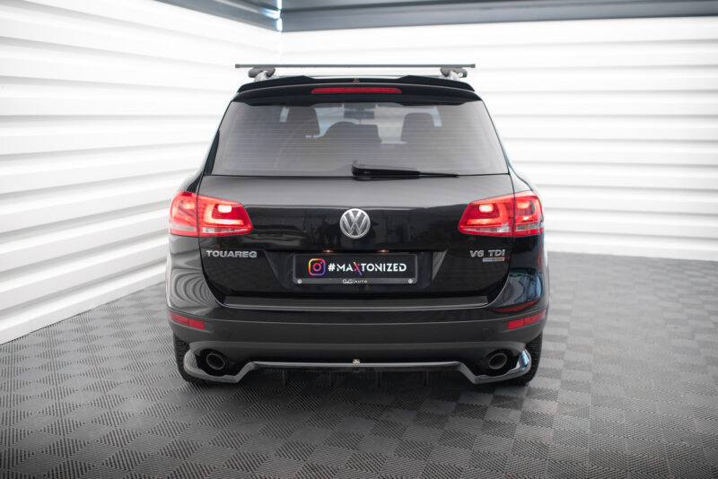 Rear view of a black Volkswagen Touareg SUV with a roof rack, parked in a bright studio setting