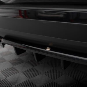 Close-up of a glossy black car rear bumper with a small Maxton Design badge visible on the chrome trim.
