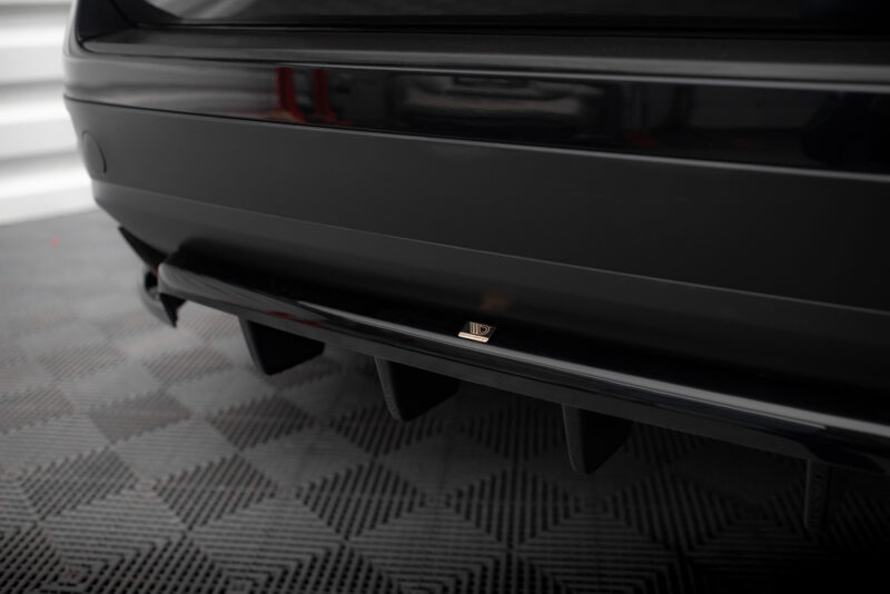 Close-up of a glossy black car rear bumper with a small Maxton Design badge visible on the chrome trim.