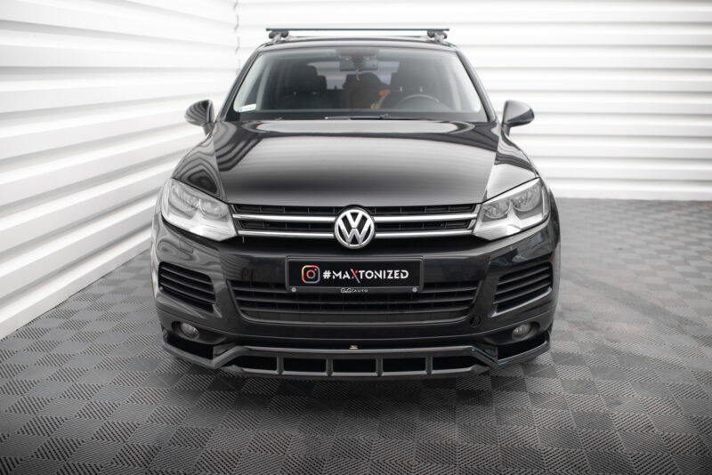 Front view of a black Volkswagen SUV with a roof rack, parked in a white panel backdrop; license plate reads '#MAXTONIZED'