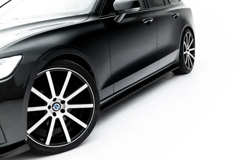 pol_po_Set-of-Splitters-Volvo-V60-R-Design-Mk3-23996_1webp - OPSHOLDERS Close-up of a black car's side, showing the front wheel and sleek door with chrome mirror against a white background, angled view.