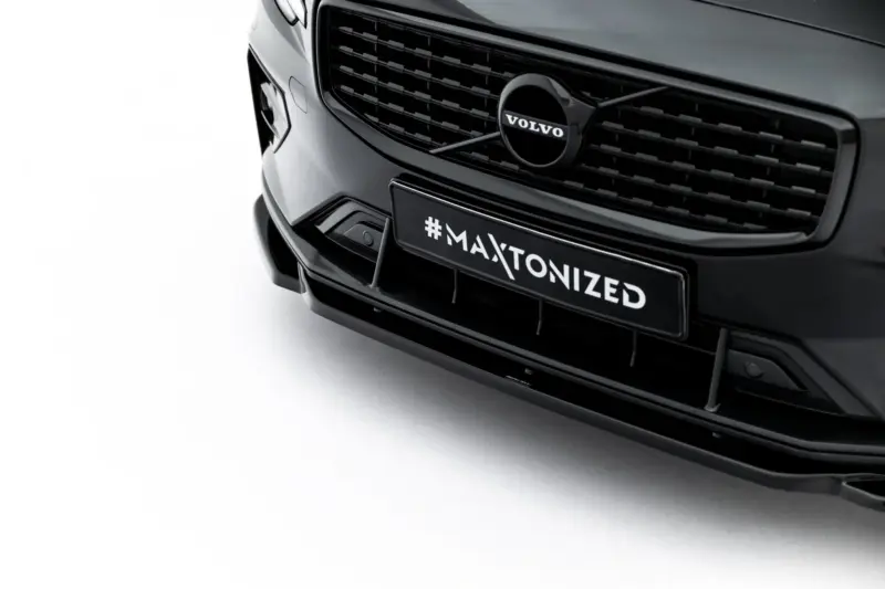 pol_po_Set-of-Splitters-Volvo-V60-R-Design-Mk3-23996_17webp - OPSHOLDERS Close-up of a black Volvo car front, showing the grille, emblem, and a license plate reading #MAXTONIZED.
