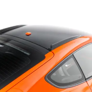 Top-down view of an orange car showing a black roof, rear window, and small orange antenna on the roof rail area.