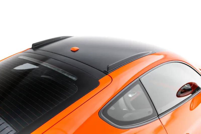 Top-down view of an orange car showing a black roof, rear window, and small orange antenna on the roof rail area.