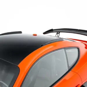 Close-up of an orange sports car roof with a black panoramic section and a large rear wing/spoiler above the rear window.