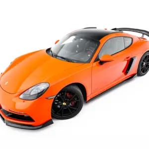 Bright orange Porsche sports car viewed from an elevated front-left angle, with a black roof and large rear spoiler.