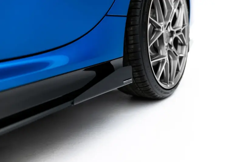 pol_po_Side-Flaps-BMW-2-M235i-Gran-Coupe-M-Pack-F74-23844_3webp - OPSHOLDERS Close-up of a blue car body near the wheel, showing the black lower trim and a large silver alloy wheel with a low-profile tire