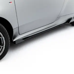 Close-up of a grey sports car's front wheel and side panel, displaying alloy wheel, low-profile tire, and a red brake caliper behind sleek spokes (GR badge visible).