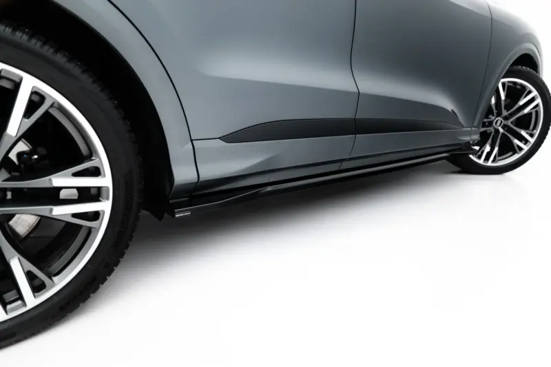 Close-up of a gray car's side panel and alloy wheel, showing smooth curves and a black trim along the door.