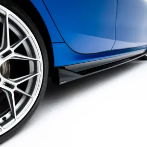 Close-up of a blue sports car's side panel with a prominent silver multi-spoke wheel and red brake calipers visible in the background.