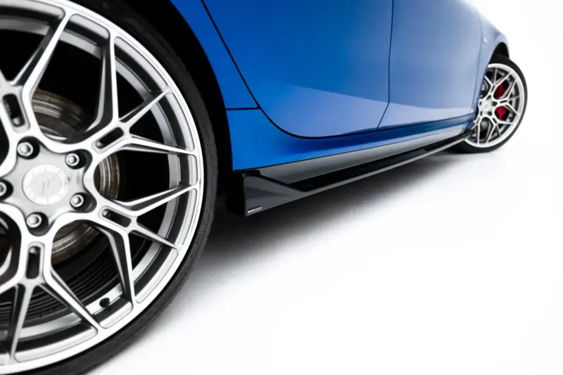 pol_po_Side-Skirts-Diffusers-BMW-2-M235i-Gran-Coupe-M-Pack-F74-23854_6webp - OPSHOLDERS Close-up of a blue sports car's side panel with a prominent silver multi-spoke wheel and red brake calipers visible in the background.
