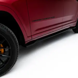 Close-up of a red Jeep Grand Cherokee side panel, showing the Grand Cherokee badge and a black alloy wheel with a yellow brake caliper.