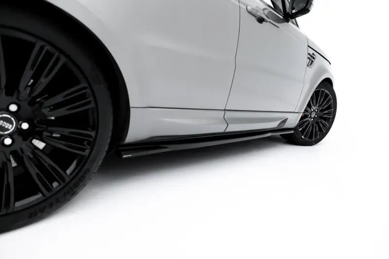 Close-up of a white car's side, featuring black alloy wheels and sleek body lines against a white background.
