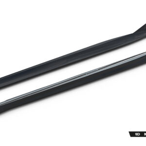 Two long black automotive trim pieces laid diagonally on a white background, likely side-sill/edge moldings from a Maxton Design body kit.