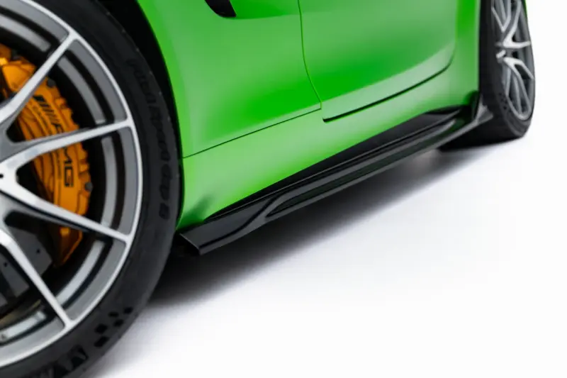 Close-up of a bright green sports car wheel with an orange brake caliper behind it.