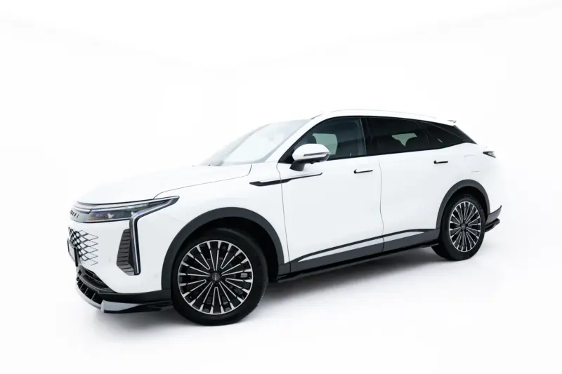 White SUV shown from a front-side angle in a studio, highlighting large black alloy wheels and chrome trim on a white background.