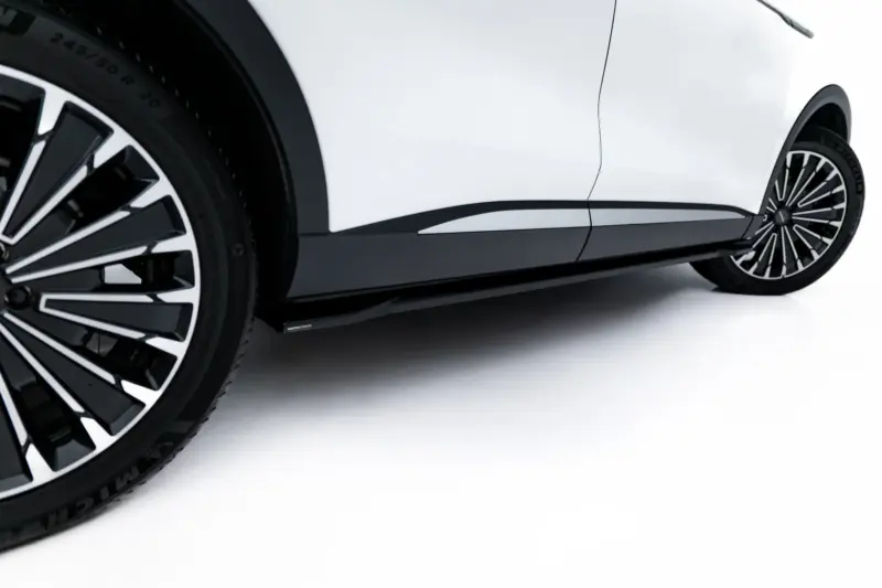 Close-up of a white car's wheel and lower body panel with a black multi-spoke alloy rim.