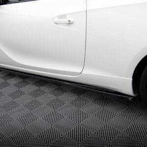 Close-up of a white car's side door, handle visible, with a black wheel and textured showroom floor beneath.