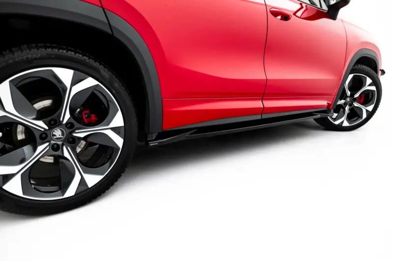 Close-up of a red car showing the door panel and front wheel with a black and silver alloy rim.