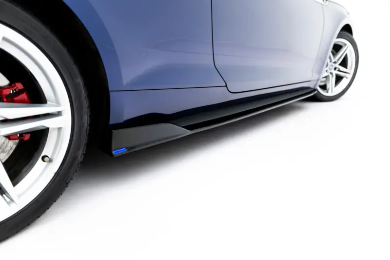 Close-up of a blue car's side panel and wheel, showing a silver alloy wheel with a red brake caliper behind it