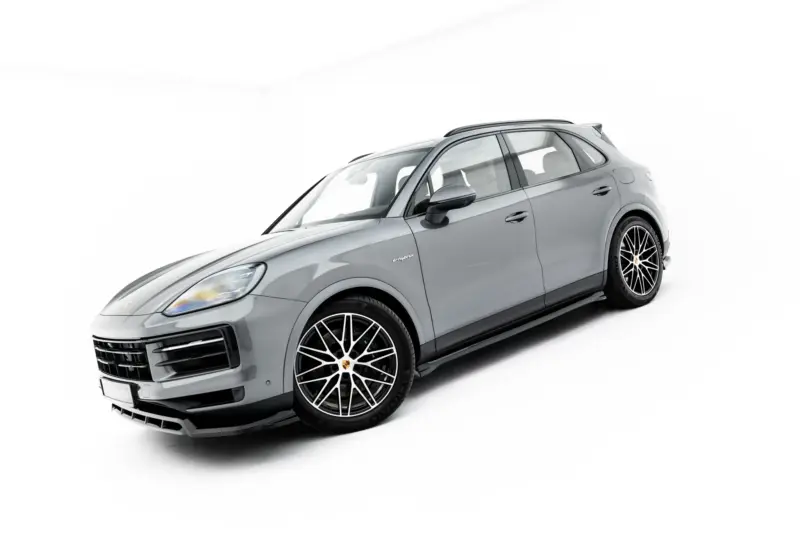 Side-front view of a silver Porsche SUV in a white studio setting, showing large alloy wheels and the hybrid badge.
