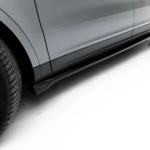 Close-up of a grey car's lower side panel and wheel, showing alloy rims and tire tread from a low-angle side view.