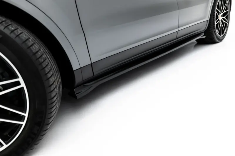 Close-up of a grey car's lower side panel and wheel, showing alloy rims and tire tread from a low-angle side view.