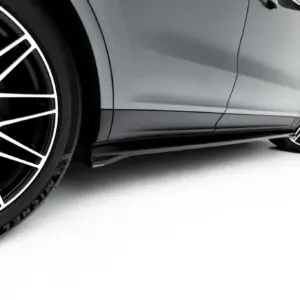 Close-up of a gray Porsche showing a large black-and-white multi-spoke wheel and brake caliper with Porsche crest on the hub.