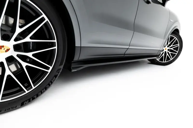 Close-up of a gray Porsche showing a large black-and-white multi-spoke wheel and brake caliper with Porsche crest on the hub.