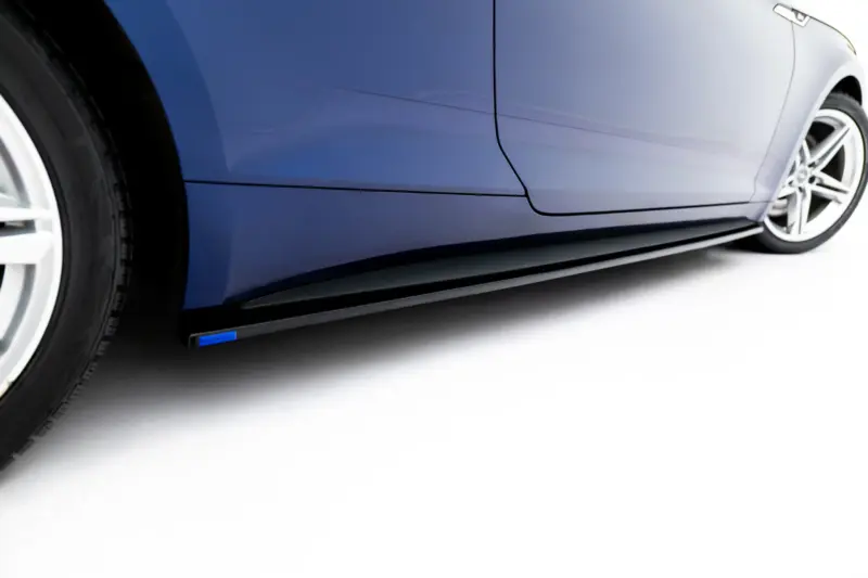 Close-up of a blue car's side panel and alloy wheel, showing the car's sleek body line and wheel rim details
