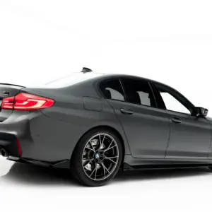 Rear three-quarter view of a dark gray BMW M4 with quad exhausts and sporty alloy wheels, shown on a white studio background.