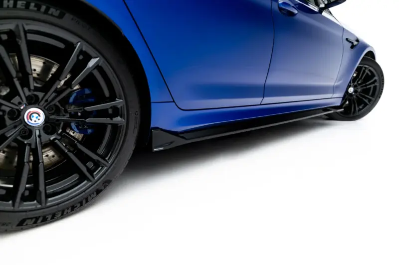Close-up of a blue sports car showing a large black alloy wheel with braking components visible and the car body in the background.