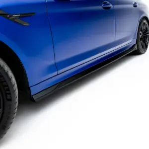 Close-up of a blue sports car's side panel, wheel and low side skirt, with an M badge on the vent.