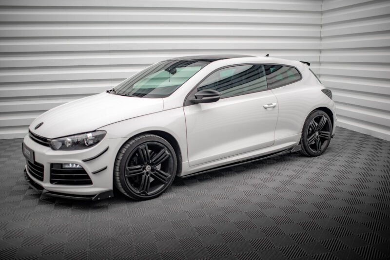 White sports car parked indoors against a striped wall with dark alloy wheels on a checkered floor.