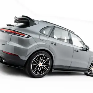 Rear three-quarter view of a silver Porsche SUV with a prominent spoiler, red taillights, and large alloy wheels