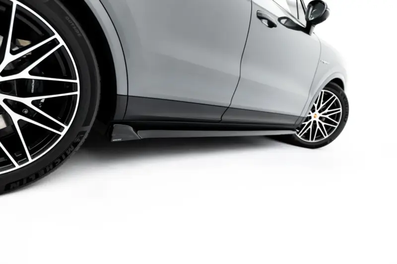 Close-up of a gray Porsche car's side panel and front wheel with a large black-and-white multi-spoke rim.