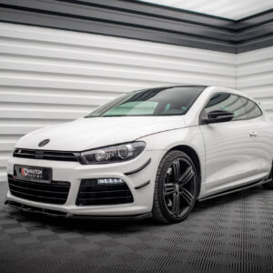 Front three-quarter view of a white Volkswagen sports car parked indoors against a corrugated metal wall.