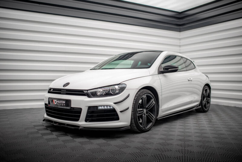 Front three-quarter view of a white Volkswagen sports car parked indoors against a corrugated metal wall.