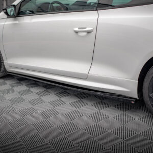 Side view of a white car showing the door and black alloy wheel on a patterned floor.
