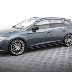 Blue metallic sedan photographed in a studio, displaying alloy wheels and roof rails on a checkered floor.