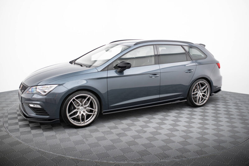 Blue metallic sedan photographed in a studio, displaying alloy wheels and roof rails on a checkered floor.