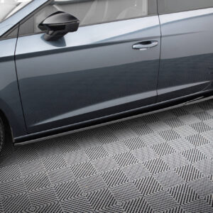 Side view of a blue-gray car showing two doors, handles, and a large alloy wheel on a patterned floor surface with reflections on the body.