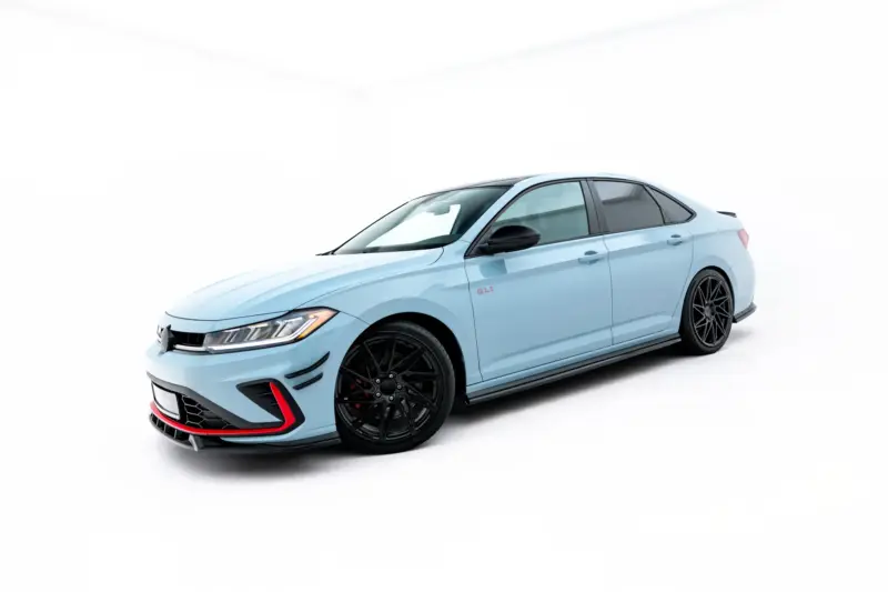 Light blue sports sedan angled in a bright white studio, front-left view with black rims and red accents on the bumper edge.