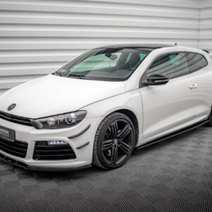 Front three-quarter view of a white Volkswagen sports hatchback in a showroom with a gray striped wall behind it with black alloy wheels visible on the right.