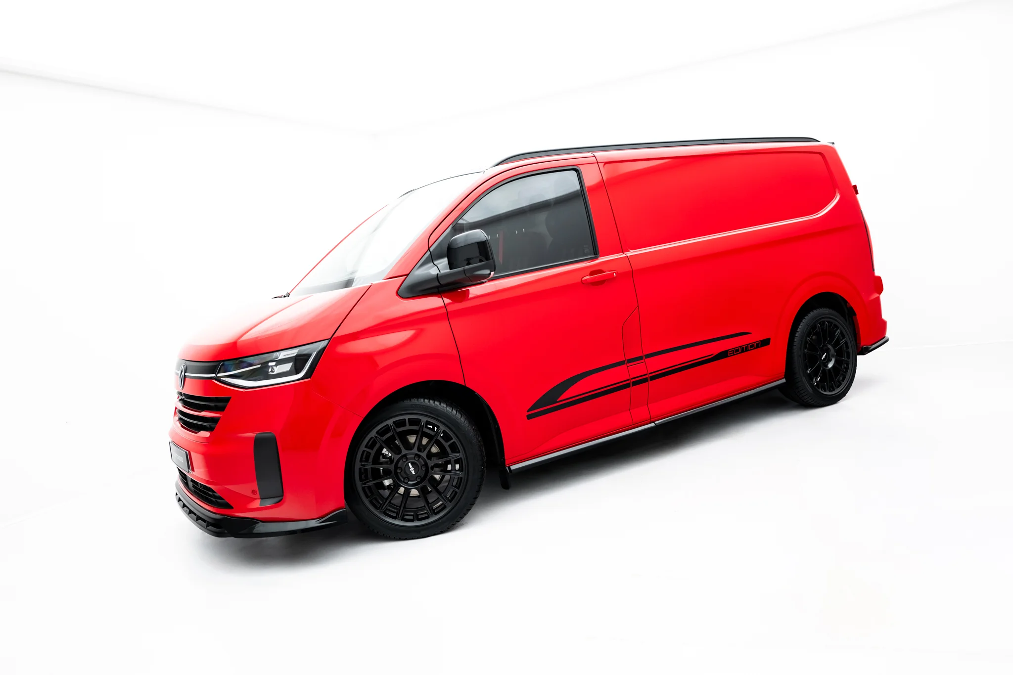 pol_po_Side-Skirts-Diffusers-Volkswagen-Transporter-L1-T7-23939_3webp - OPSHOLDERS Red van shown from a side-front angle with black alloy wheels in a white studio setting.