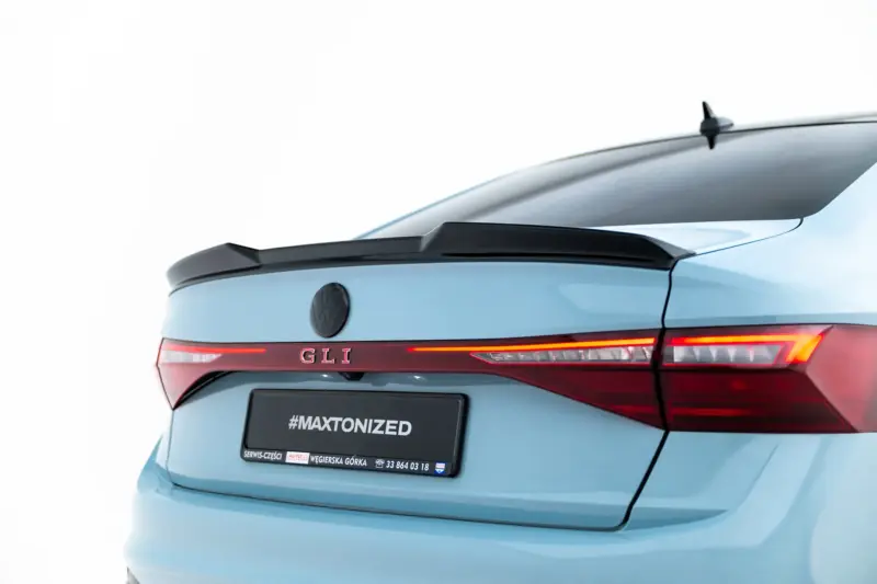 Rear of a light blue Volkswagen hatchback with GLI badge, VW emblem, and red taillights; license plate reads #MAXTONIZED.
