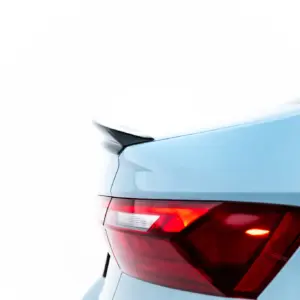 Rear left corner of a light blue car showing the tail light and trunk edge.